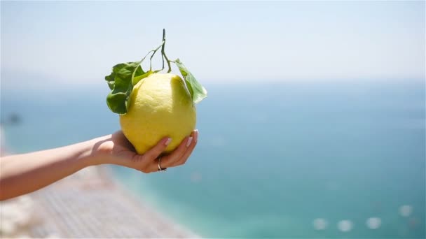 Grande limão amarelo na mão no fundo do mar mediterrâneo e céu . — Vídeo de Stock