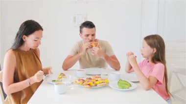 Mutlu bir aile mutfakta kahvaltı yapıyor.