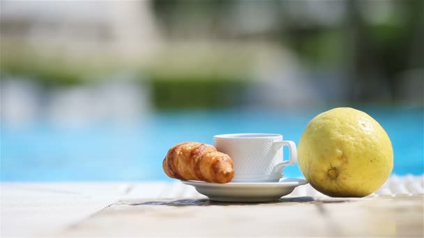 Вкусный завтрак лимон, кофе, круассан у бассейна — стоковое видео