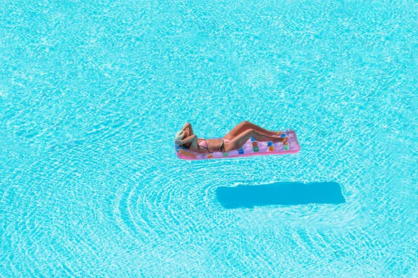 Jonge vrouw in bikini luchtmatras in het grote zwembad — Stockfoto