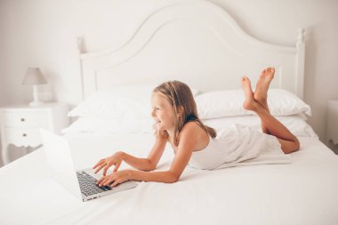 Dizüstü bilgisayarda ödev yapan sevimli küçük kız.