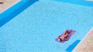 Büyük yüzme havuzunda bikini hava şilte genç kadın