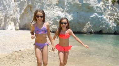 Küçük kızlar yaz tatilinde tropik plajda eğleniyorlar.