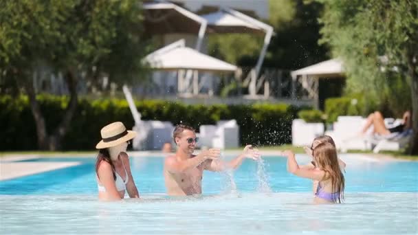 Familia feliz de cuatro en la piscina al aire libre — Vídeos de Stock