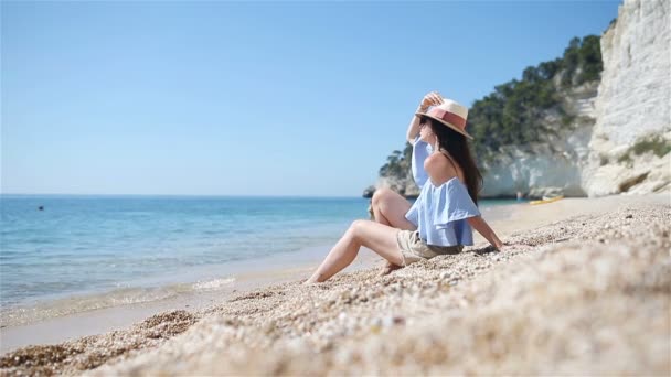 Plajda uzanan kadın yaz tatilinin tadını çıkarıyor ve denize bakıyor. — Stok video