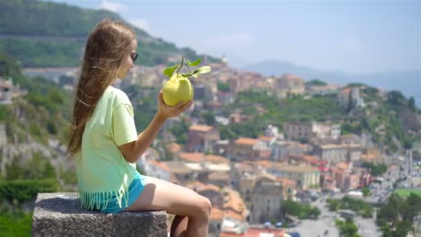 Big yellow lemon in hand in background of mediterranean sea and sky. — Stock Video