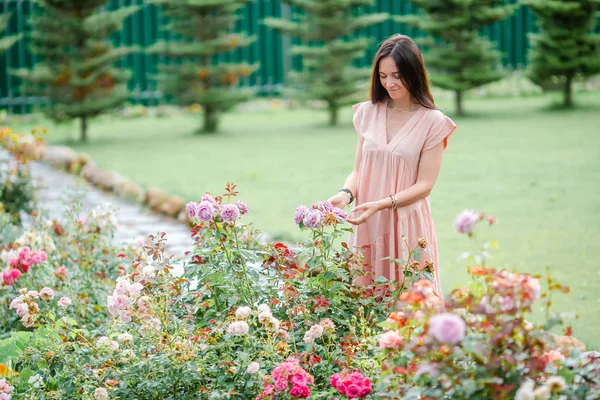 아름다운 장미 사이의 화원에 있는 소녀. 장미향 — 스톡 사진