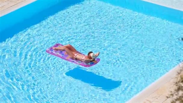 Jonge vrouw in bikini luchtmatras in het grote zwembad — Stockvideo