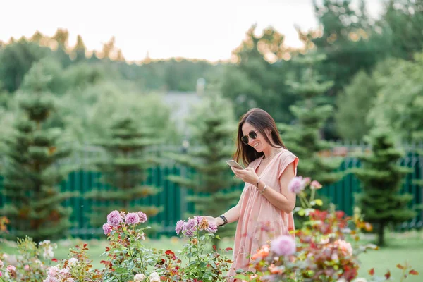 Ung flicka i en blomsterträdgård bland vackra rosor. Lukt av rosor — Stockfoto