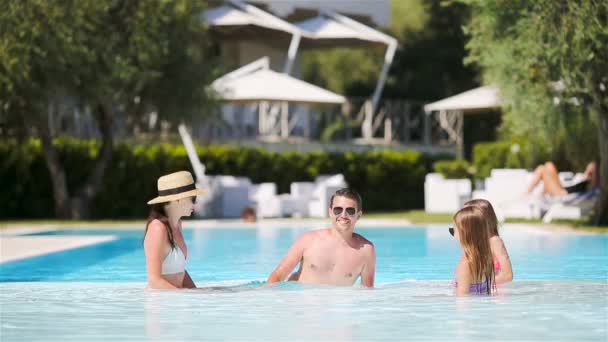 Familia feliz de cuatro en la piscina al aire libre — Vídeo de stock