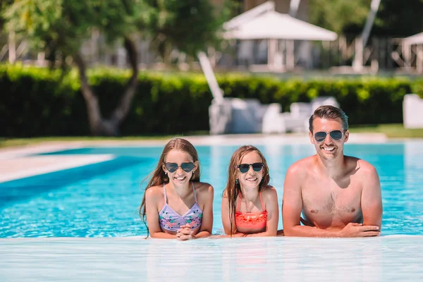 Happy family of four in outdoors swimming pool — Stock Photo, Image