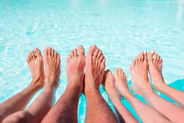 Közelről négy népek lábak a medence oldalán — Stock Fotó