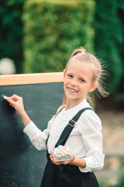 Happy little schoolgirl with a chalkboard outdoor — Stock Photo, Image