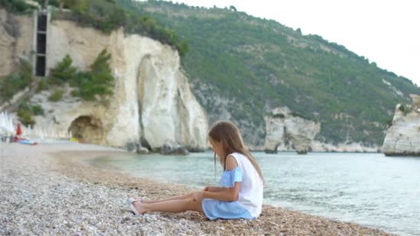 Schattig klein meisje aan het strand tijdens de zomervakantie — Stockvideo
