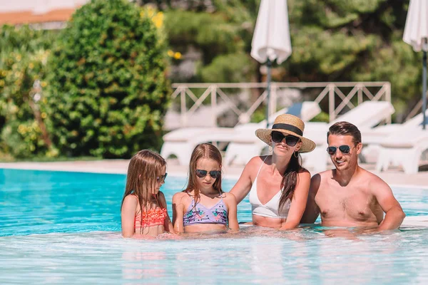 Happy family of four in outdoors swimming pool — Stock Photo, Image