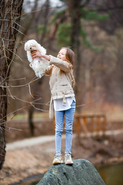 Beyaz köpek yavrusu olan küçük bir kız. Bir kızın ellerinde bir köpek yavrusu — Stok fotoğraf