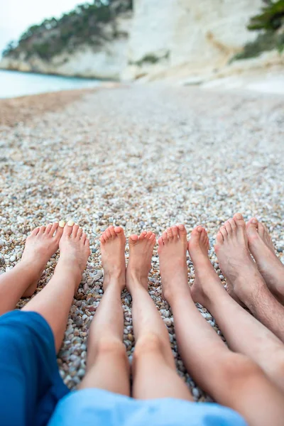 Närbild av fötterna av familjen på den vita sandstranden — Stockfoto