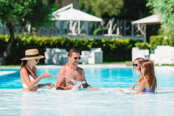 Familia feliz de cuatro en la piscina al aire libre — Foto de Stock