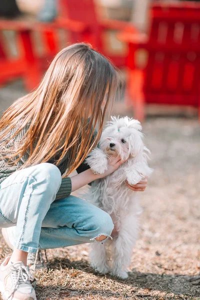 Kleines Mädchen mit einem weißen Welpen. Ein Welpe in den Händen eines Mädchens — Stockfoto