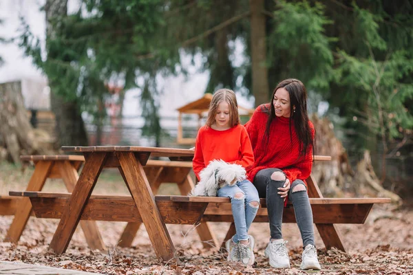 Schattig klein meisje en jonge moeder met puppy outdoor — Stockfoto