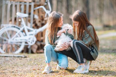 Beyaz köpek yavrusu olan küçük kızlar. Bir kızın elinde bir köpek yavrusu