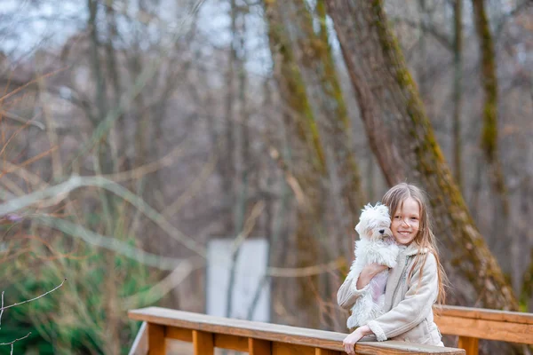 En liten flicka med en vit valp. En valp i händerna på en flicka — Stockfoto
