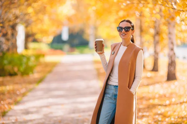 Concept d'automne - belle femme buvant du café dans le parc d'automne sous le feuillage d'automne — Photo