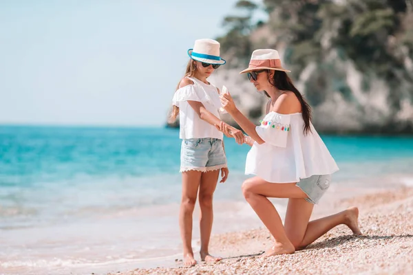 Madre aplicando crema de protección solar a su hija en la playa tropical — Foto de Stock