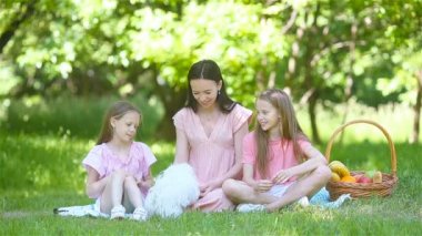 Mutlu anne ve küçük kızları göl kenarında dinleniyor.