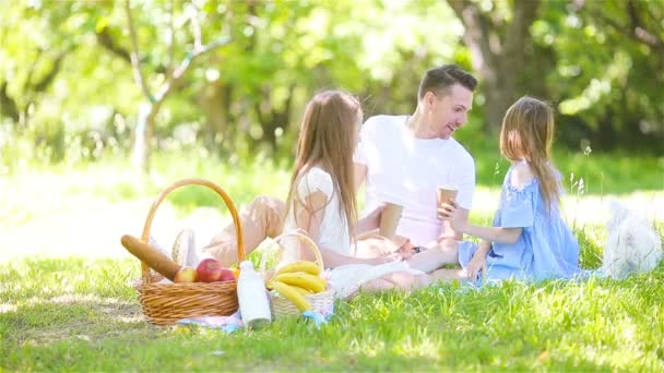 Счастливый отец и маленькие дочери отдыхают у озера — стоковое видео