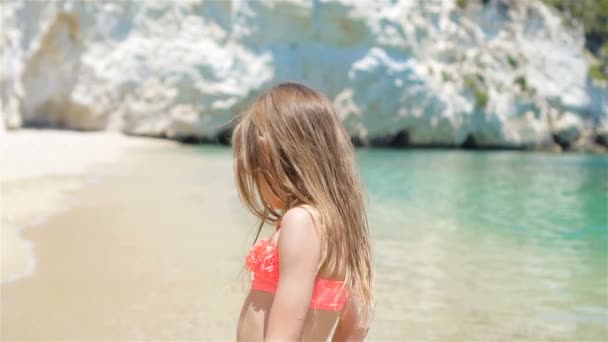 Aktives kleines Mädchen am Strand, das viel Spaß hat. Nettes Kind macht sportliche Übungen an der Küste — Stockvideo