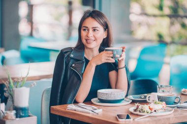 Sonbahar konsepti: Sonbahar parkında sonbahar yaprakları altında kahve içen güzel bir kadın.