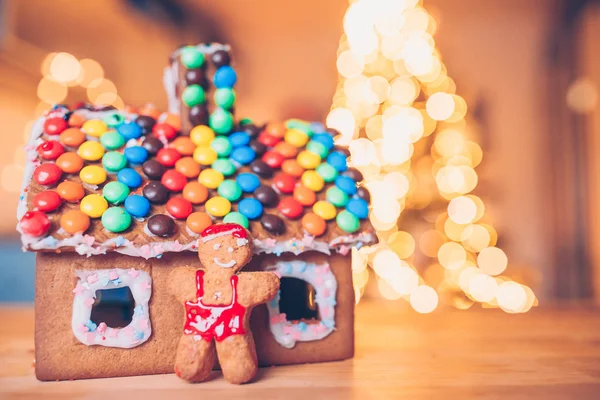 Lebkuchenmärchenhaus auf dem Hintergrund eines hellen Weihnachtsbaums mit Girlande — Stockfoto