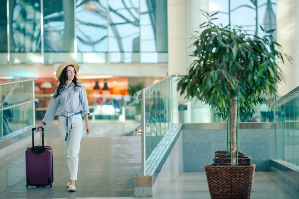 Ung kvinna i hatt med bagage på internationell flygplats. — Stockfoto