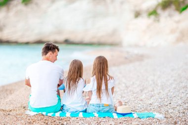 Baba ve iki kızı sahilde.