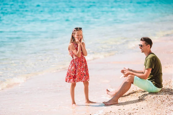 Pai aplicando creme de proteção solar para sua filha na praia tropical — Fotografia de Stock