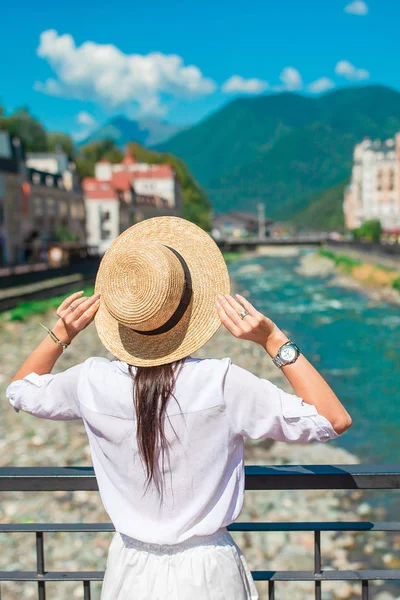 Ευτυχισμένος κορίτσι στο καπέλο για το ανάχωμα του ένα ποτάμι βουνό σε μια ευρωπαϊκή πόλη. — Φωτογραφία Αρχείου