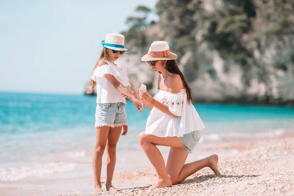 Mother applying sun protection cream to her daughter at tropical beach — Stock Photo, Image