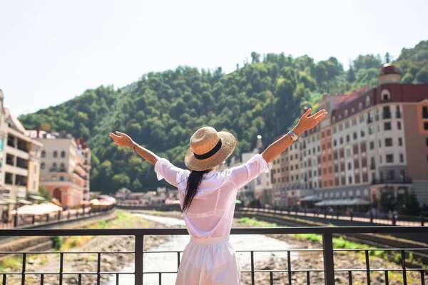 Happy girl at hat on the embankment of a mountain river in a European city. — Stock Photo, Image