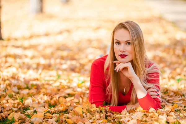 Herbstkonzept - schöne Frau trinkt Kaffee im Herbstpark unter Herbstlaub — Stockfoto