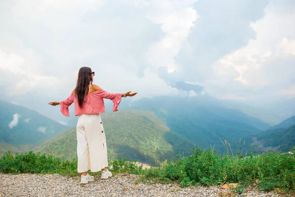 Mulher jovem feliz bonita em montanhas no fundo do nevoeiro — Fotografia de Stock