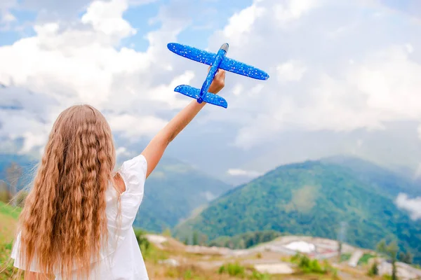 Menina feliz com avião de brinquedo nas mãos em montanhas — Fotografia de Stock