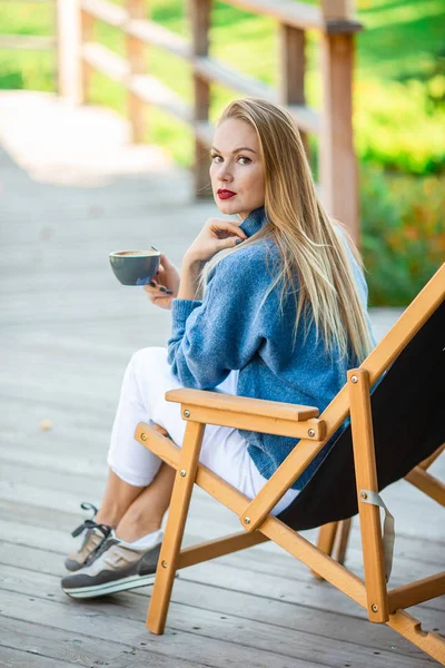 Herbstkonzept - schöne Frau trinkt Kaffee im Herbstpark unter Herbstlaub — Stockfoto