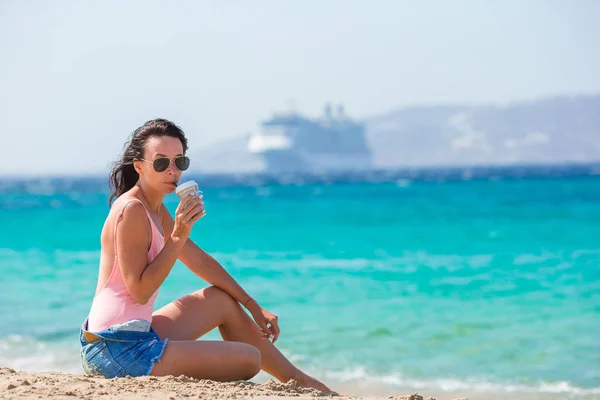 Jonge mooie vrouw met koffie op het strand tijdens tropische zomervakantie — Stockfoto