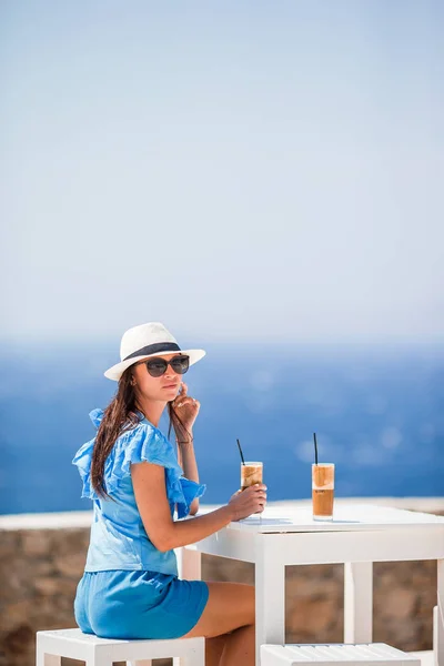 Jovem mulher bebendo café frio apreciando vista mar. — Fotografia de Stock