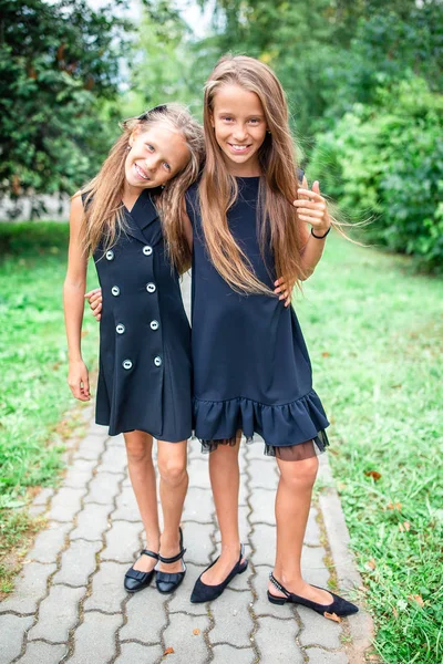 Dwie słodkie, uśmiechnięte dziewczynki pozujące przed swoją szkołą. — Zdjęcie stockowe
