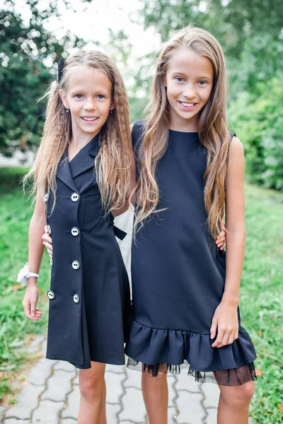 Okullarının önünde poz veren gülümseyen iki küçük kız..