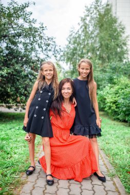 Anne ve kızları okula gidiyor. Sevimli küçük kızlar okula dönmek için çok heyecanlılar.