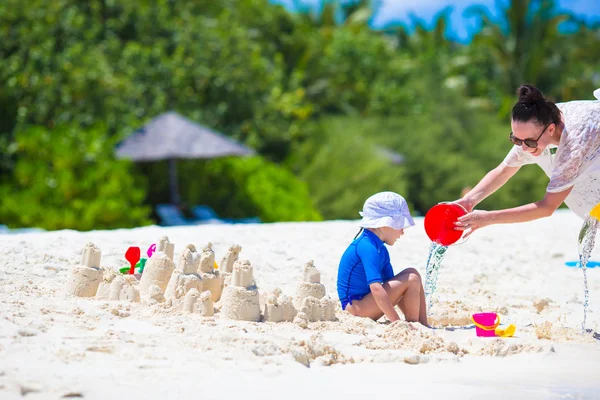 Malá holka a mladí máma hraje s hračkami, pláž na tropickou dovolenou — Stock fotografie