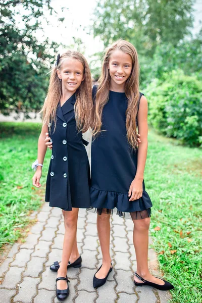 Dos lindas niñas humeantes posando frente a su escuela. — Foto de Stock